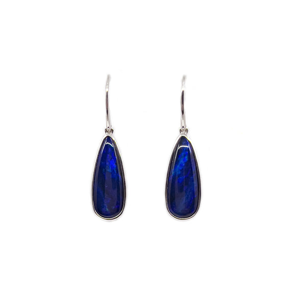 A pair of sterling silver drop earrings, each featuring an elongated, teardrop-shaped Australian doublet opal with deep blue hues and vibrant flashes of color. The opals are bezel-set, providing a smooth, polished finish to the design. The earrings dangle elegantly from simple silver hooks, catching the light to reveal the opal's unique play of color. | Fremantle Opals